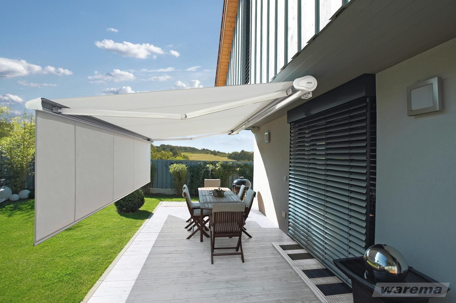 Volant Rollo für Markisen. LS Sonnenschutz Produktseite Markisen. Individuelle Markise kaufen bei LS Sonnenschutz in Groß-Umstadt.  Hellgraue Markise ausgefahren über Terrasse bei Sonnenschein mit ausgefahrenem Volant-Rollo gegen frontale tiefstehende Sonne