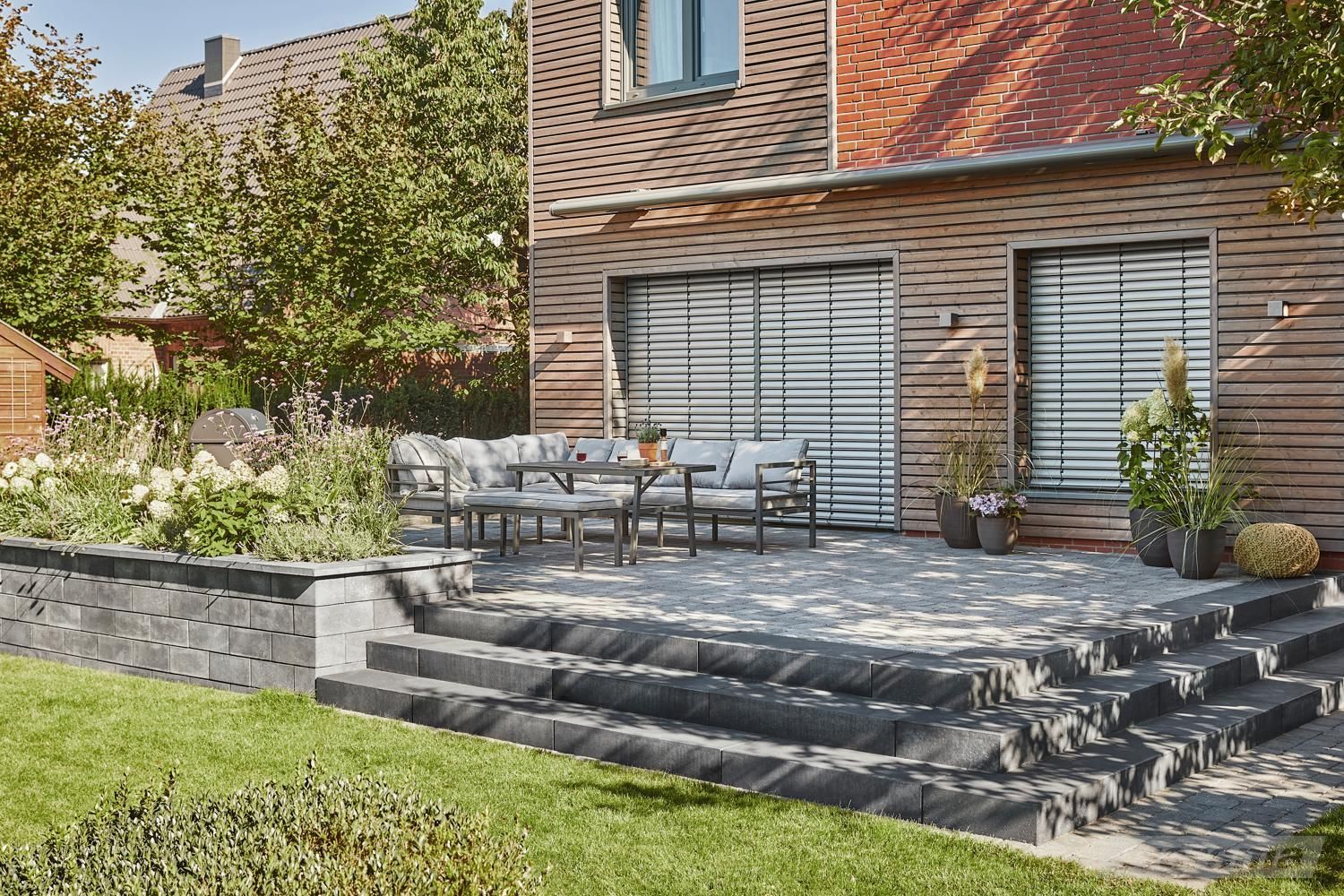 LS Sonnenschutz_Raffstore_Warema_BEG Foerderung Sicht auf Terrasse aus dem Garten im Sommer auf geschlossene Raffstore von Warema als sommerlicher Wärmeschutz