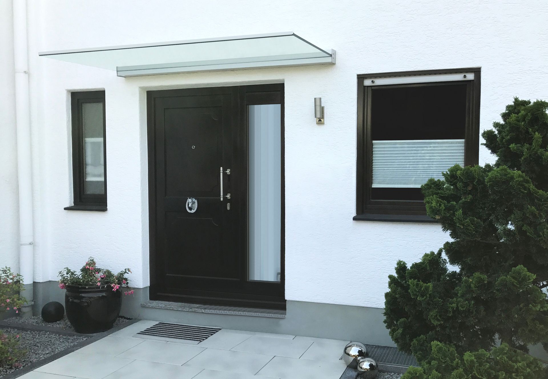 Individuelle Vordächer aus Glas für Ihren Eingangsbereich bei LS Sonnenschutz in Groß-Umstadt kaufen. Wir beraten Sie gerne zu verschiedenen Ausführungen und Modellen im Raum Darmstadt, Dieburg, Frankfurt und Rhein-Main Gebiet, Aschaffenburg, Odenwald. Modernes, freitragendes Glasvordach von Panther Glas über einer Eingangstür montiert. LS Sonnenschutz Produktseite Vordächer.