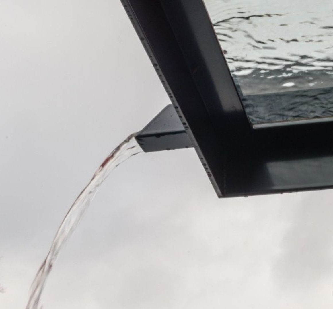 Detailansicht: ablaufendes Wasser über Regenablaufrinne von Panther Glas Vordachsystemen. LS Sonnenschutz Produktseite Vordächer, optionale Ausstattungsmerkmale. 