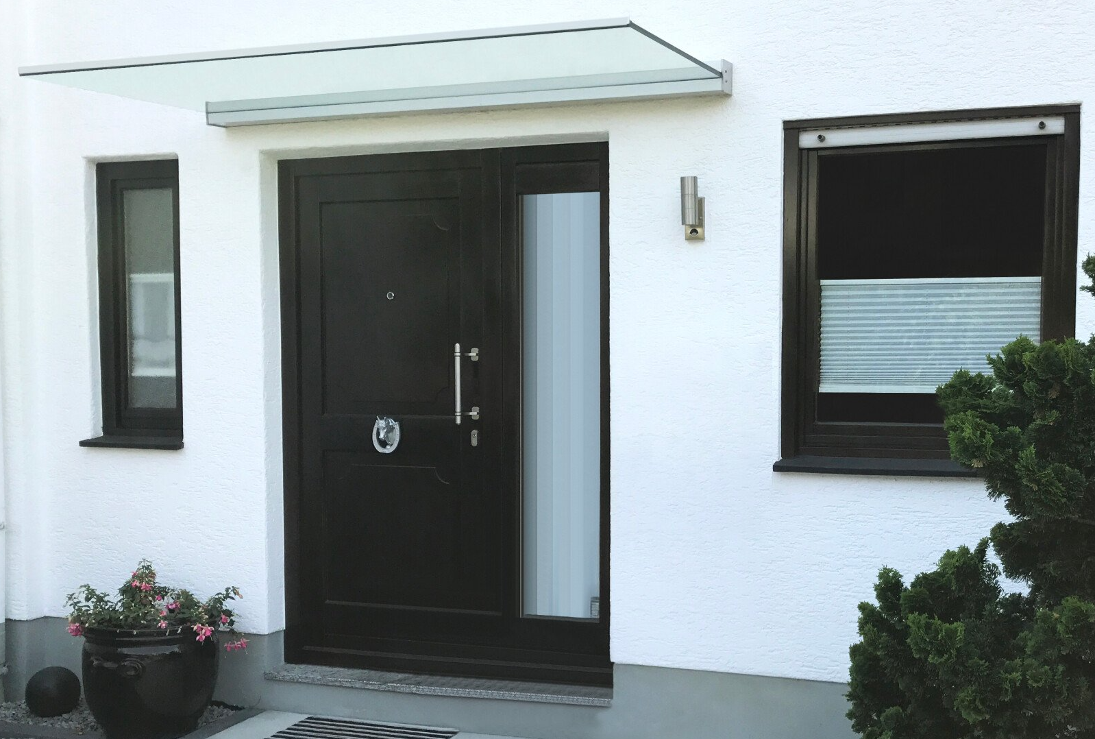 Glas Vordach von Panther Glas bei LS Sonnenschutz in Groß-Umstadt kaufen. Geschützt vor Wind und Regen im Eingangsbereich vor der Haustür. Wir beraten Sie gerne zu verschiedenen Modellen und Farben im Raum Darmstadt, Dieburg, Frankfurt, Aschaffenburg, Odenwald. Panther Glas Vordach ohne Rahmen, über Eingangstür in anthrazit, Link zu Produktseite Vordächer