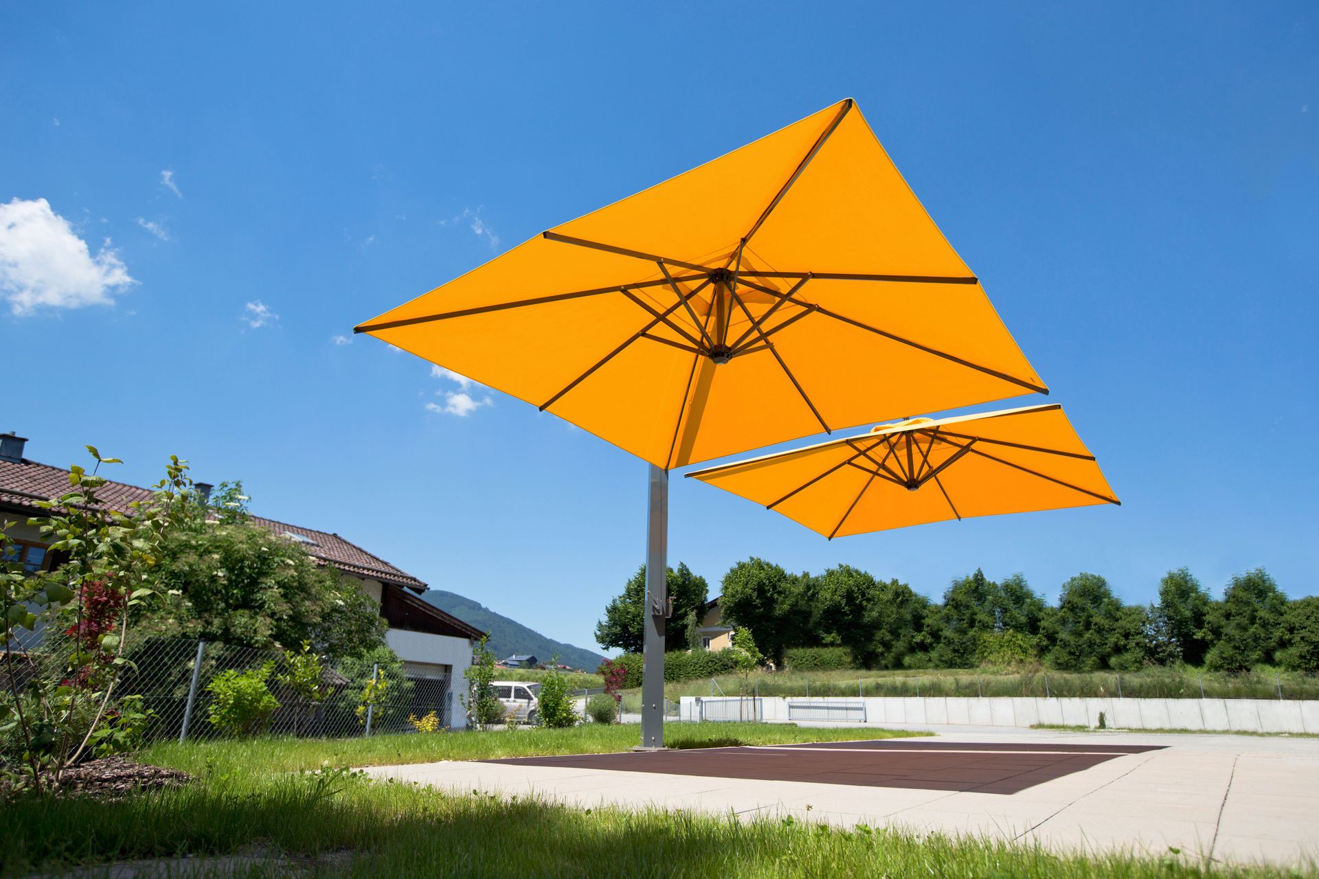 Sonnenschirm Amalfi DUO von Caravita für die Gastronomie, Balkon, Terrasse oder Garten bei LS Sonnenschutz in Groß-Umstadt kaufen. Wir beraten Sie gerne zu verschiedenen Modellen und Farben im Raum Darmstadt, Dieburg, Frankfurt, Aschaffenburg, Odenwald. Caravita Sonnenschirme Amalfi DUO, zwei Schirme mit gelb-orangener Tuchbespannung nebeneinander ueber einem gepflasterten Bereich im Garten. LS Sonnenschutz Produktseite Sonnenschirme.