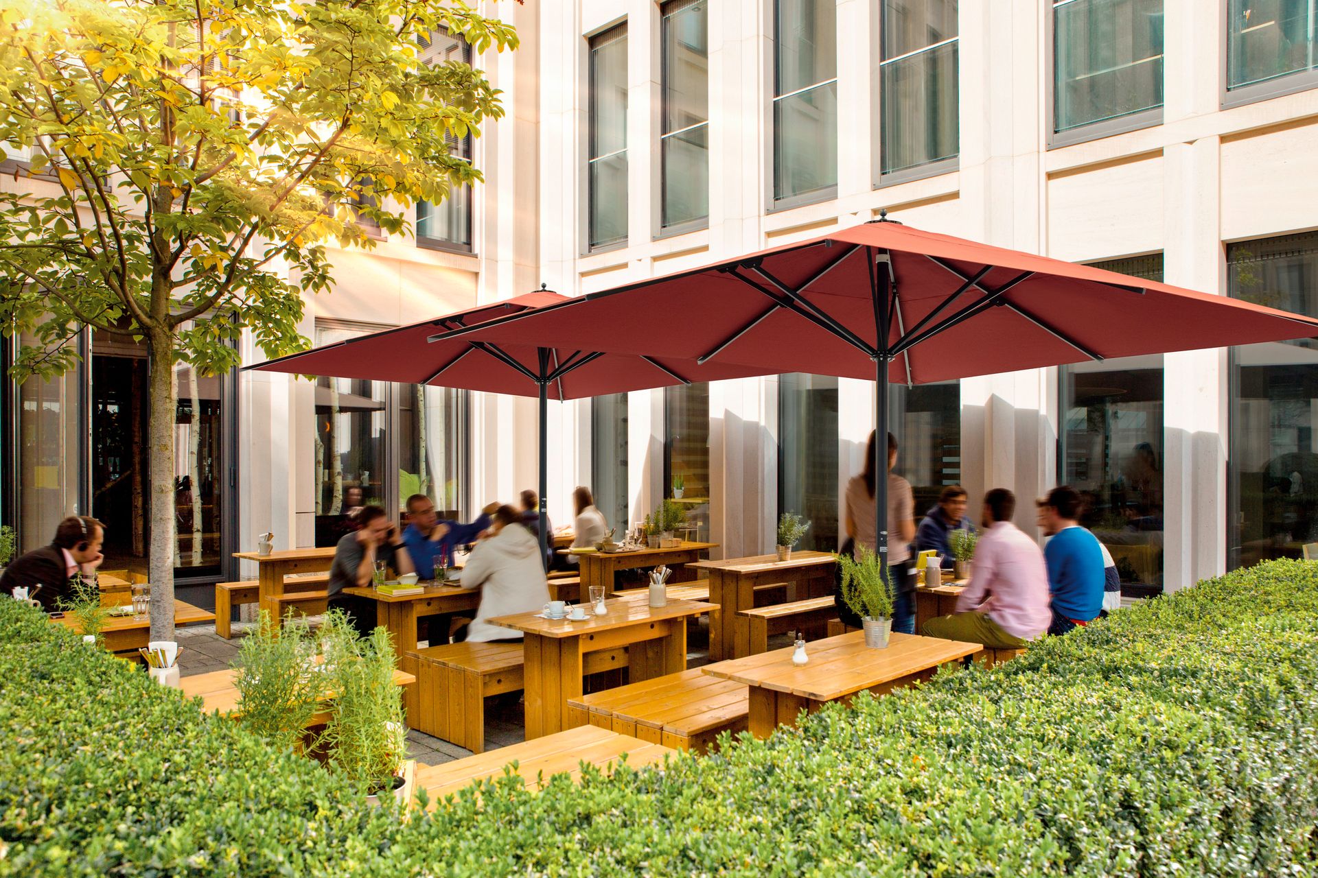 Sonnenschirm Centro von Caravita speziell für die Gastronomie bei LS Sonnenschutz in Groß-Umstadt kaufen. Wir beraten Sie gerne zu verschiedenen Modellen und Farben im Raum Darmstadt, Dieburg, Frankfurt, Aschaffenburg, Odenwald. Zwei Caravita Sonnenschirme Centro mit roter Tuchbespannung im Außenbereich eines Cafés. LS Sonnenschutz Produktseite Sonnenschirme.