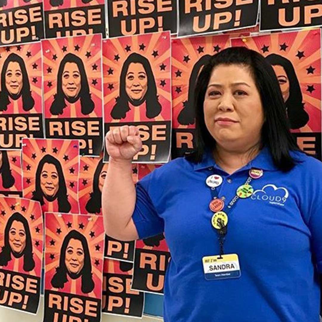 actress Kaliko Kauahi who plays sandra on superstore in front of her rise up posterron