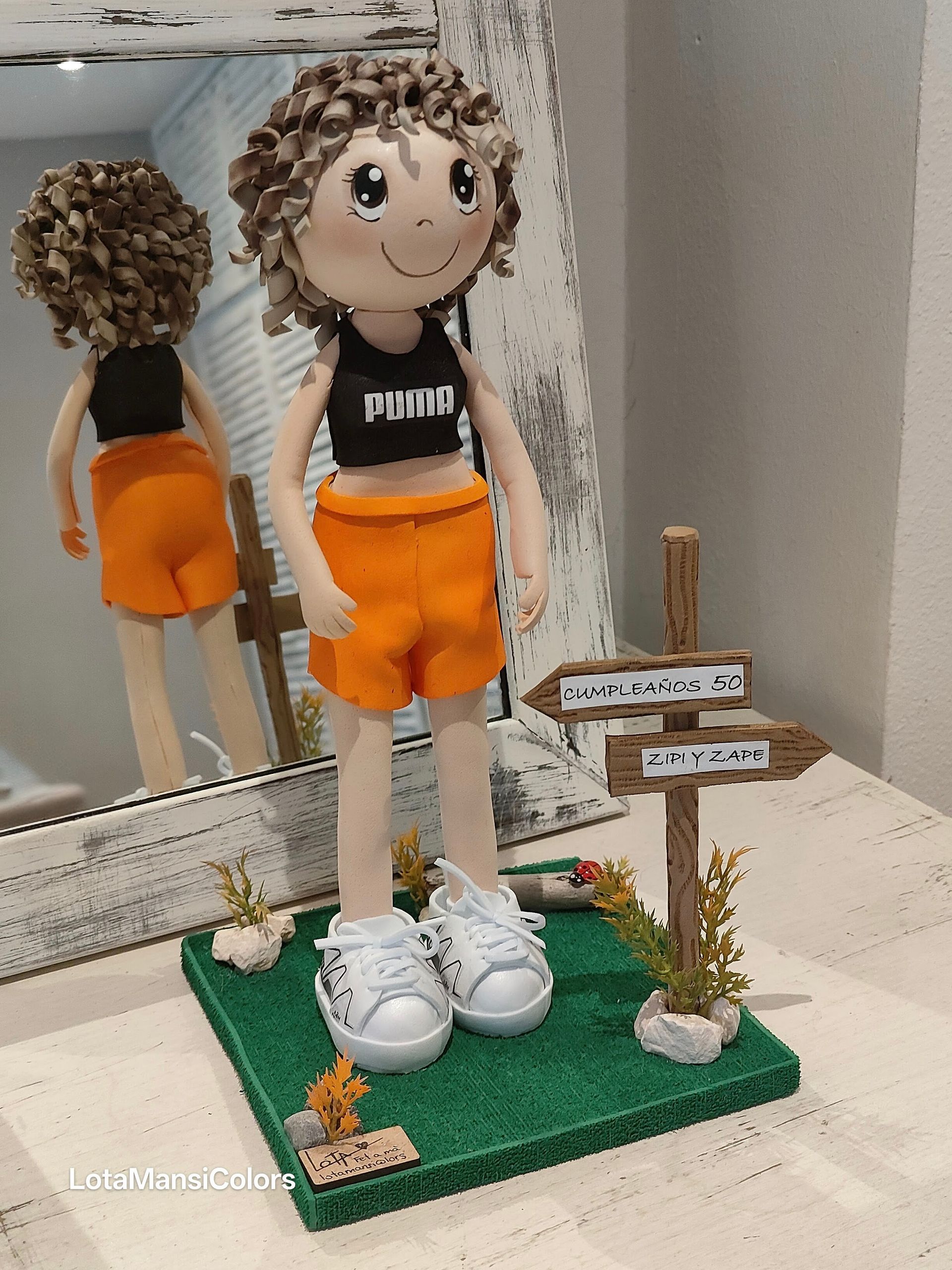 fofuchas personalizadas , mujer con pelo rubio rizado, senderismo, con pantalon corto naranja Nike, top negro Puma y bambas blancas Salomon. Fofucha personalizada