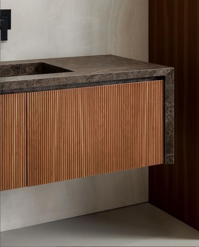A contemporary bathroom vanity with wood-textured paneling and a dark marble countertop.