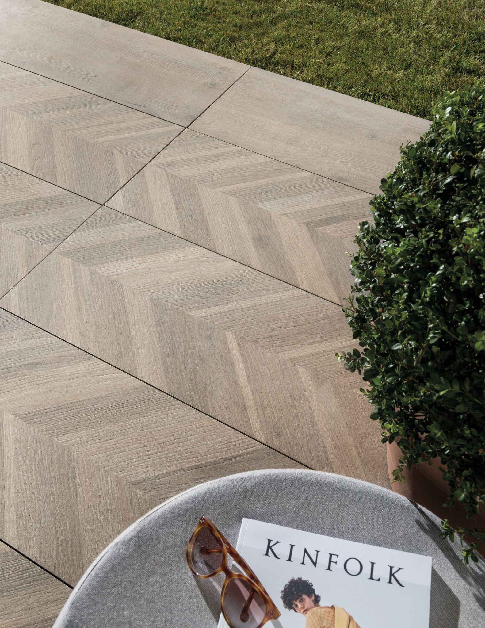 woodland tile on the floor close up with a bush in view