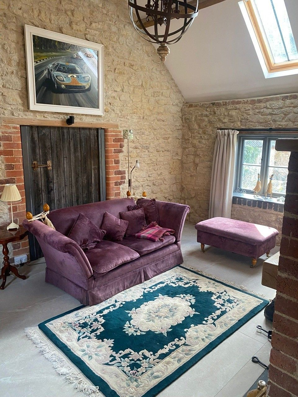 Old fashioned livingroom with a purple sofa and exposed brick