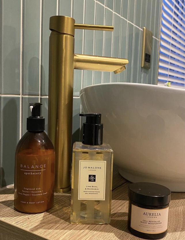 CLose up of sink and soaps with flaut green tiles