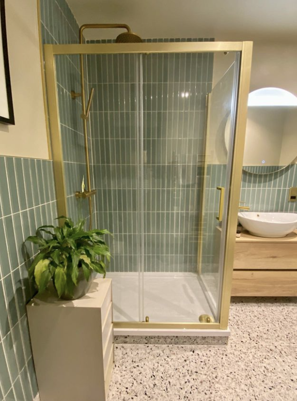golden rimed shower with faut green tiles on the wall in the bathroom