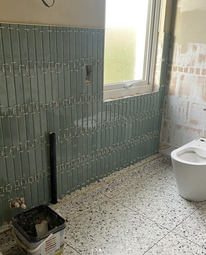 uncompleted renovated bathroom with a clear wall and a a wall with flaut teal on it