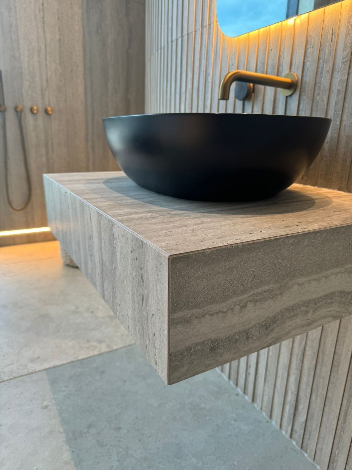 close up of bespoke travertine tiles used wit hblack sink