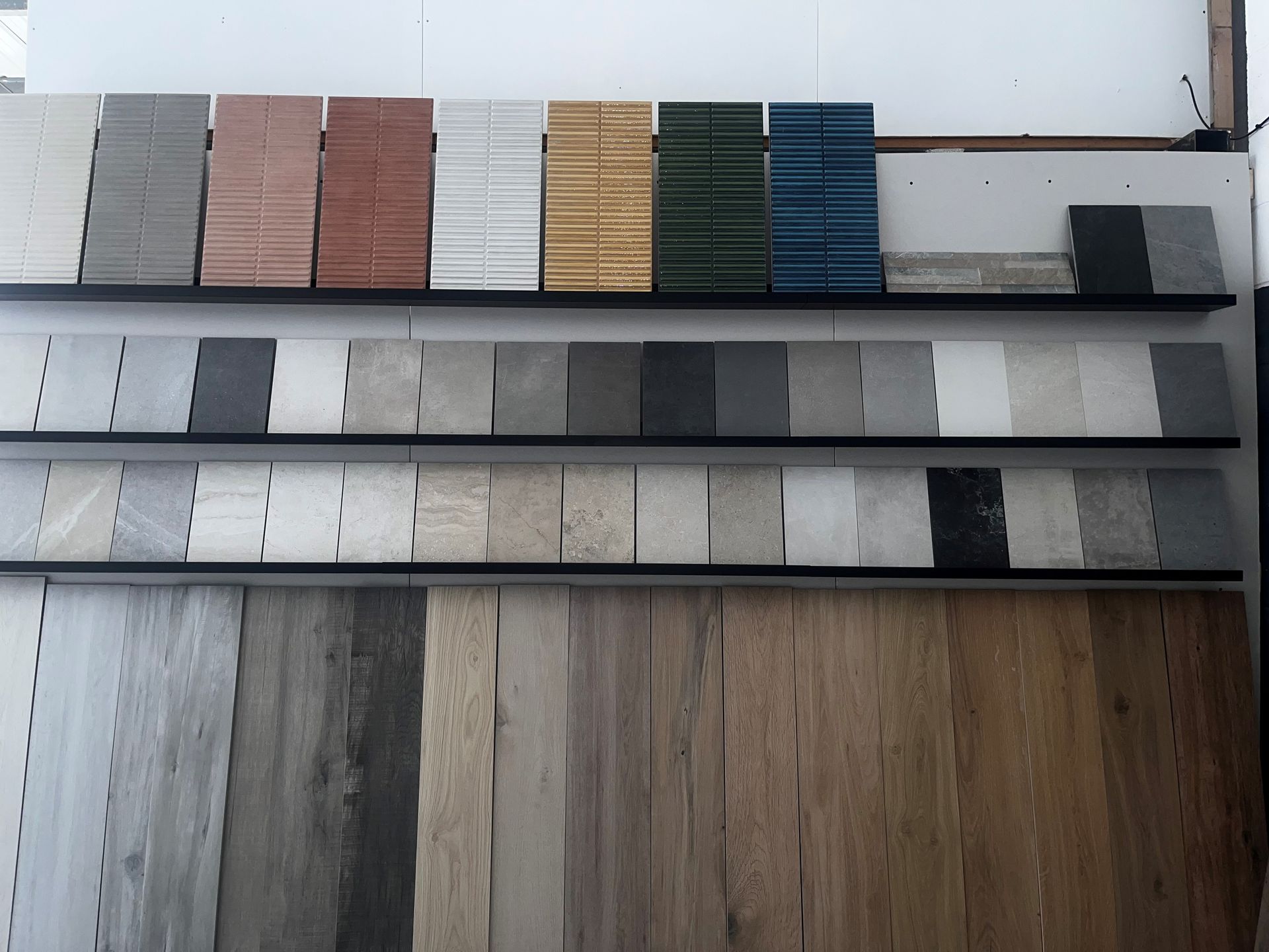 A wall of textured wall tiles in various colors and patterns, alongside wood-effect floor tiles, offering a mix of modern and rustic design.