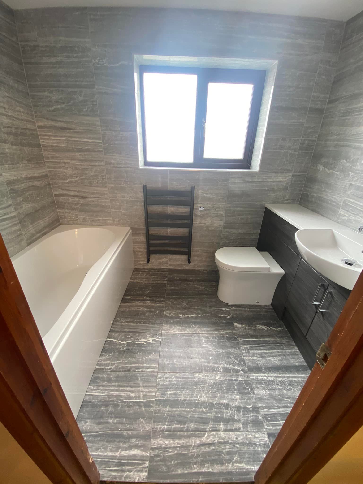 A bathroom with grey wall and floor tiles