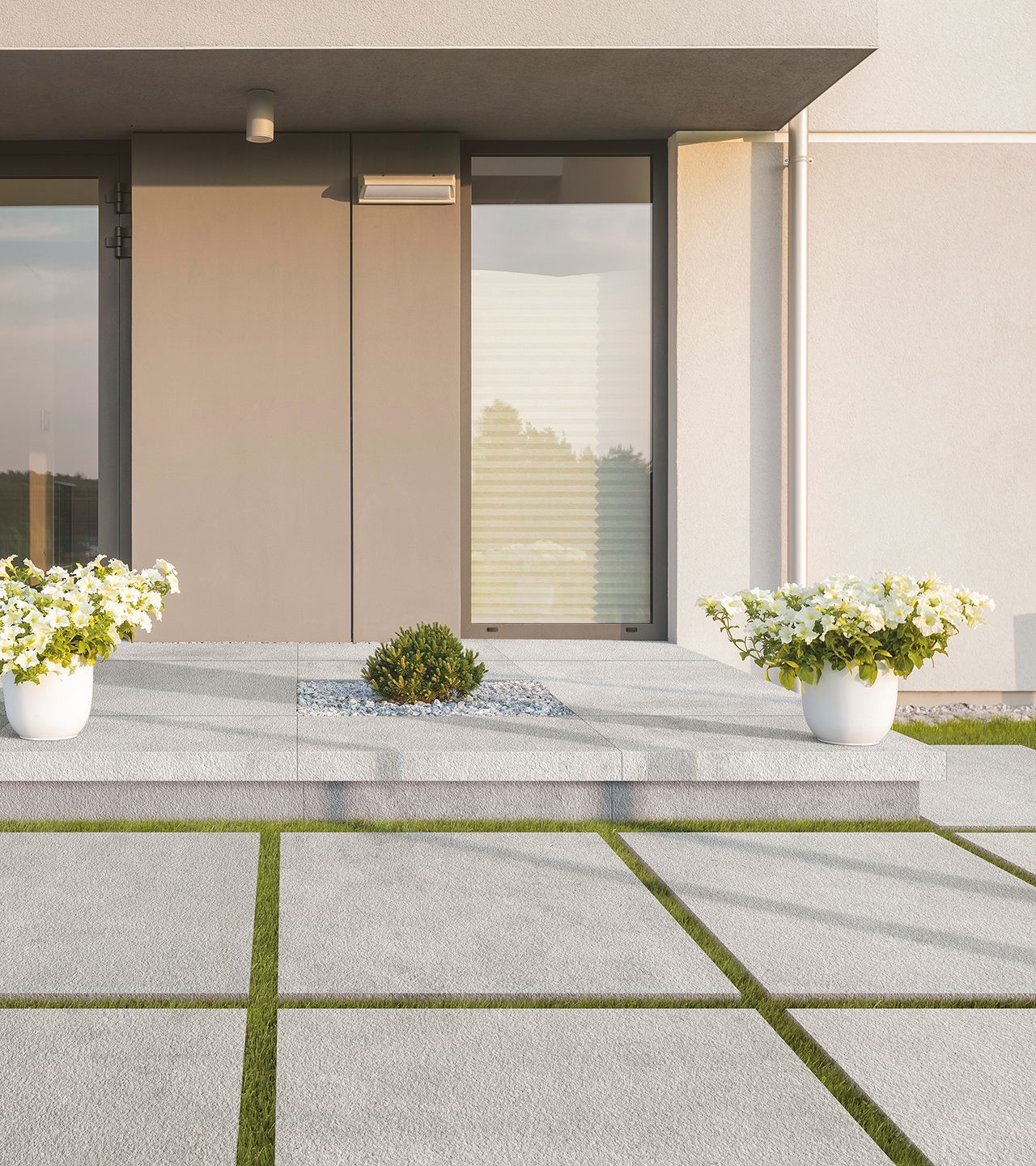 Front entrance with light gray concrete-style tiles in a grid layout. White flower pots and low grass accents frame the pathway for a clean, minimalist aesthetic.