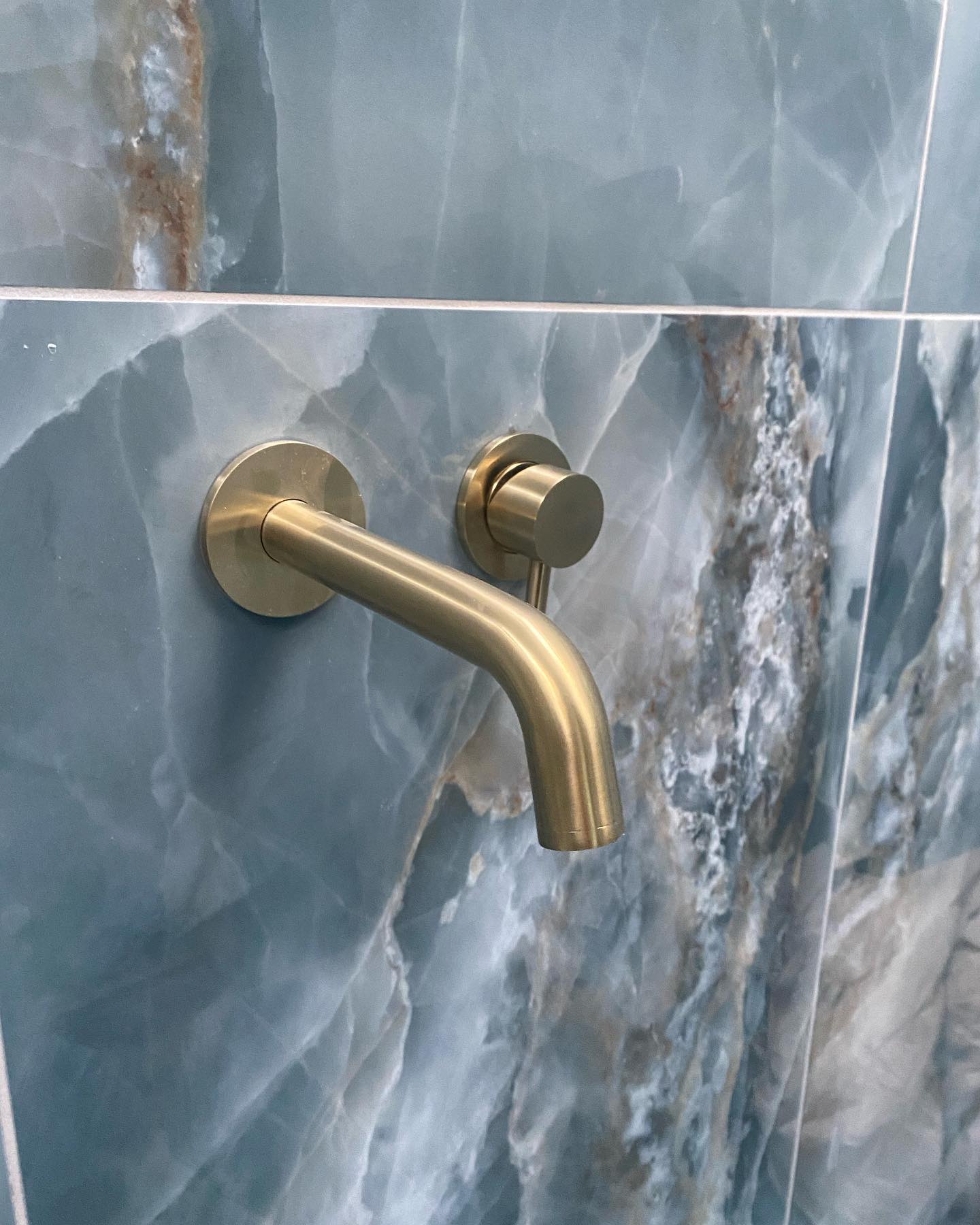 Azul tile on bathroom wall with golden tap hanning out of the wall