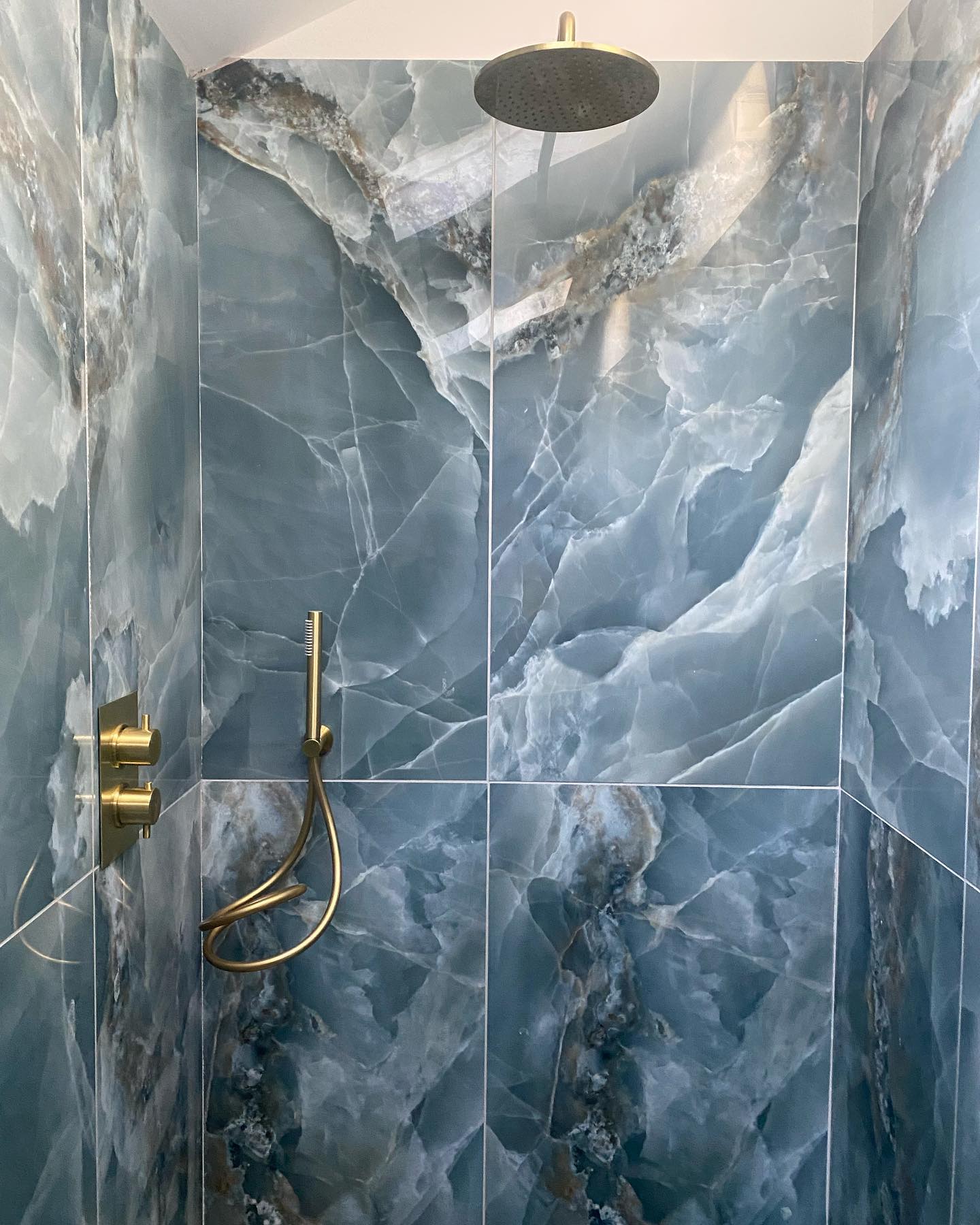 Completed Shower with blue wall tiles and golden finished taps