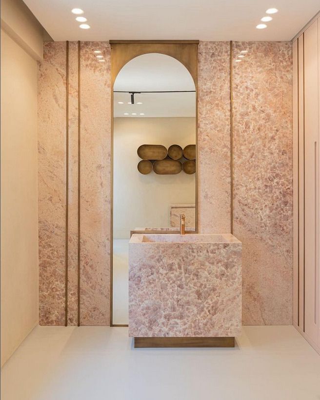 Luxurious bathroom design with soft pink stone surfaces, featuring a modern square sink and floor-to-ceiling stone panels.