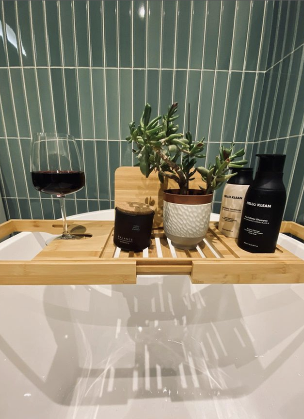 bath tray with wine and other accsesories all infornt of flaut green