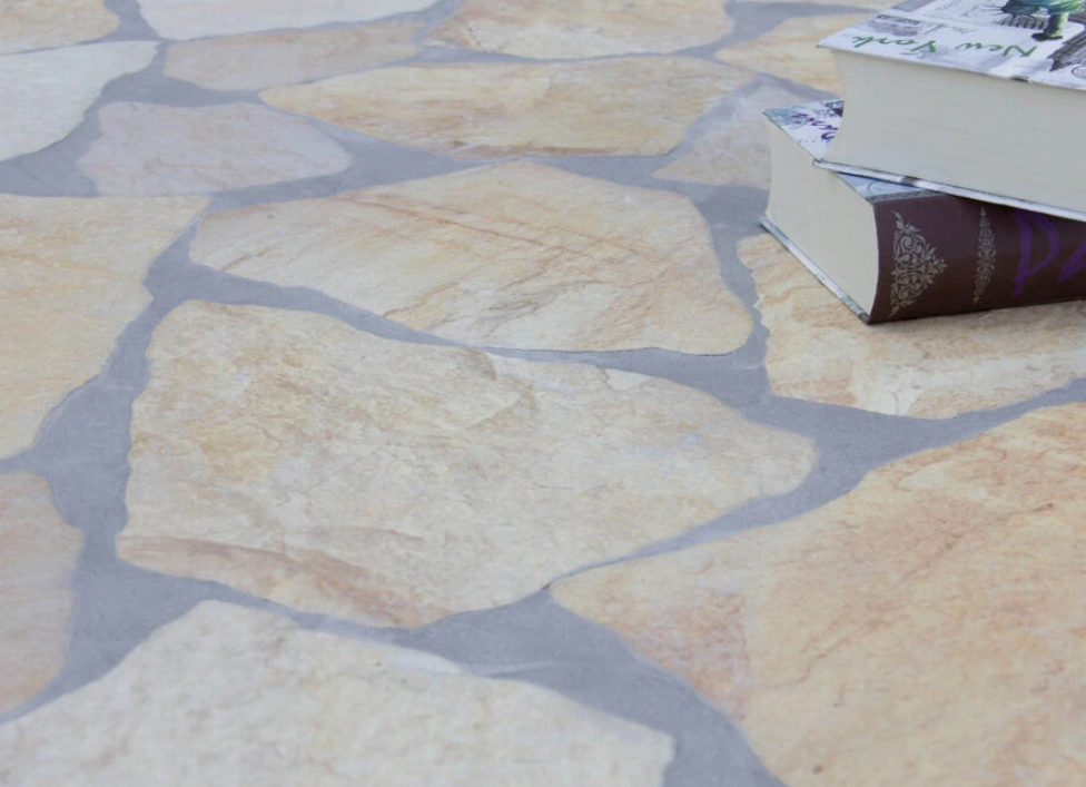Close-up of beige natural stone tiles arranged in an irregular pattern. Two stacked books rest on the tiles, highlighting the texture and earthy color tones