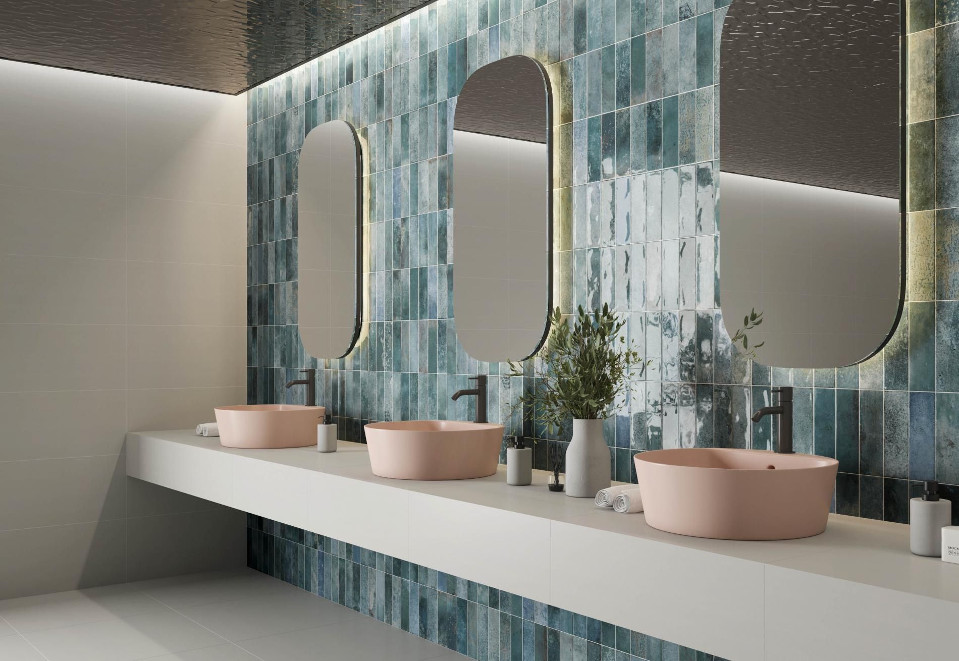 a blue brick tile used with oval mirrors and pink cylinder basins with black brassware