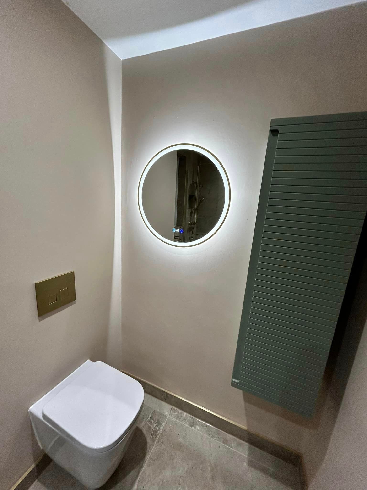 Light up mirror used in a modern bathroom with limestone effect floor tiles