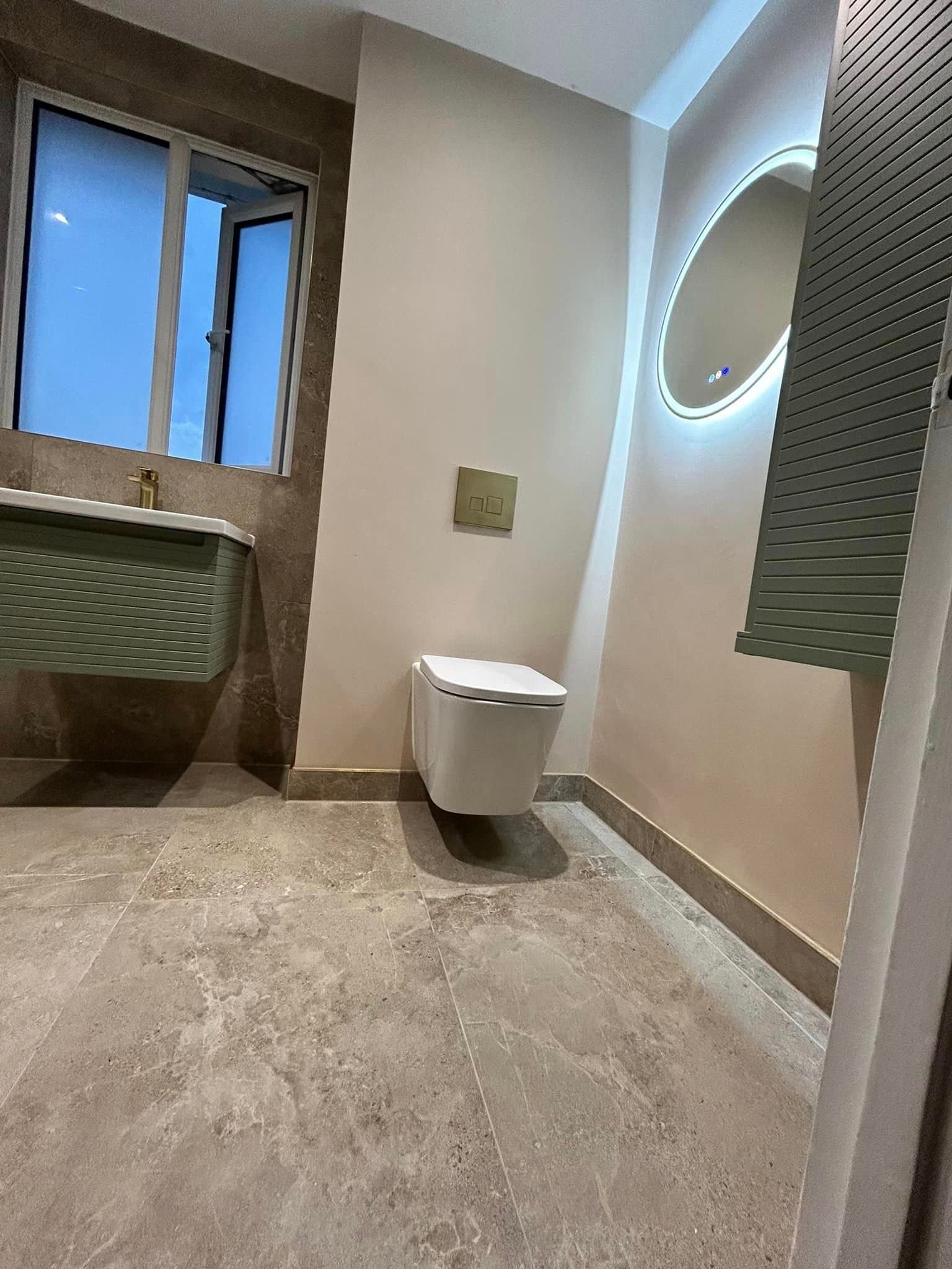 Toilet in modern bathroom with limestone effect floor tiles and a green pane