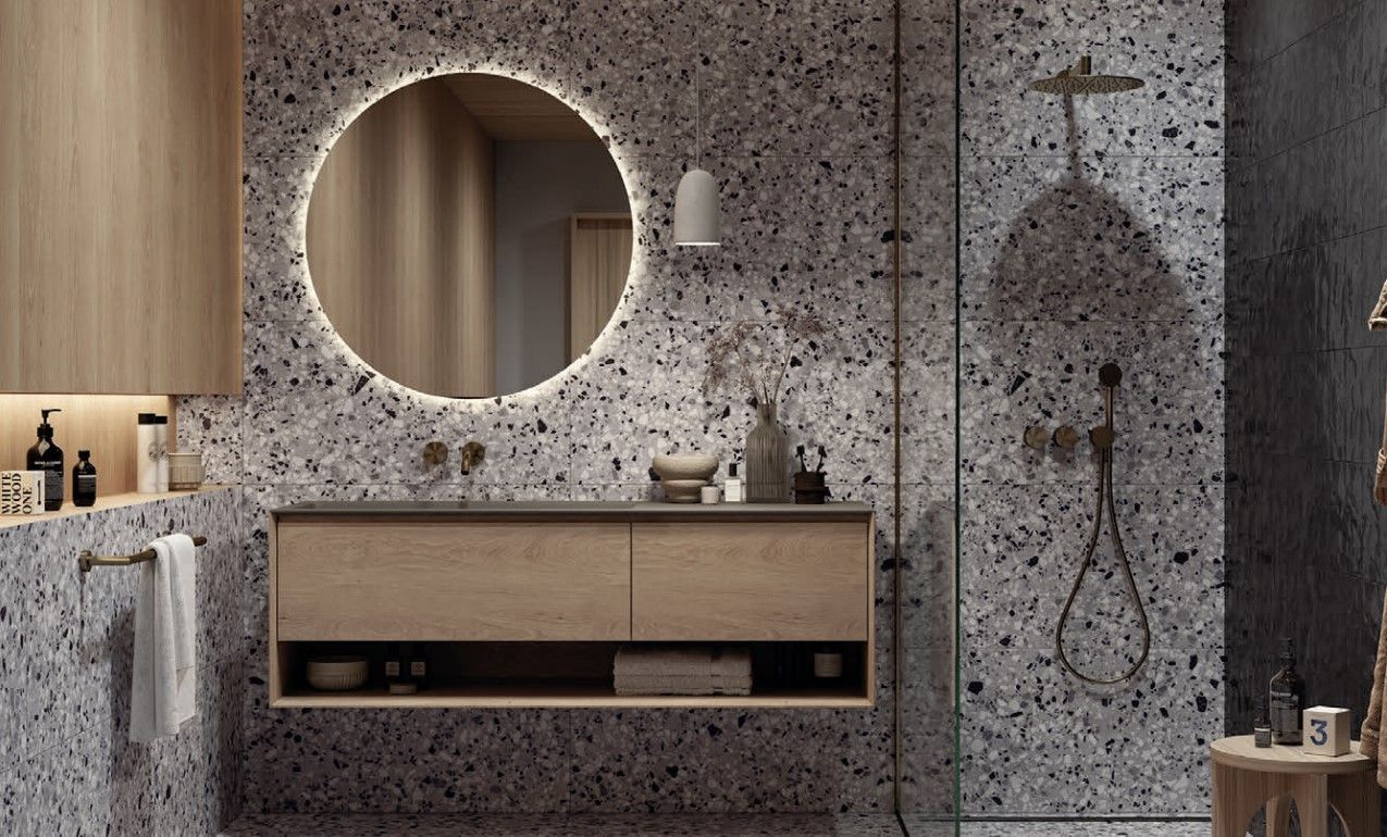 Terrazzo wall effect put to use in a modern bathroom with a light up mirror and rain