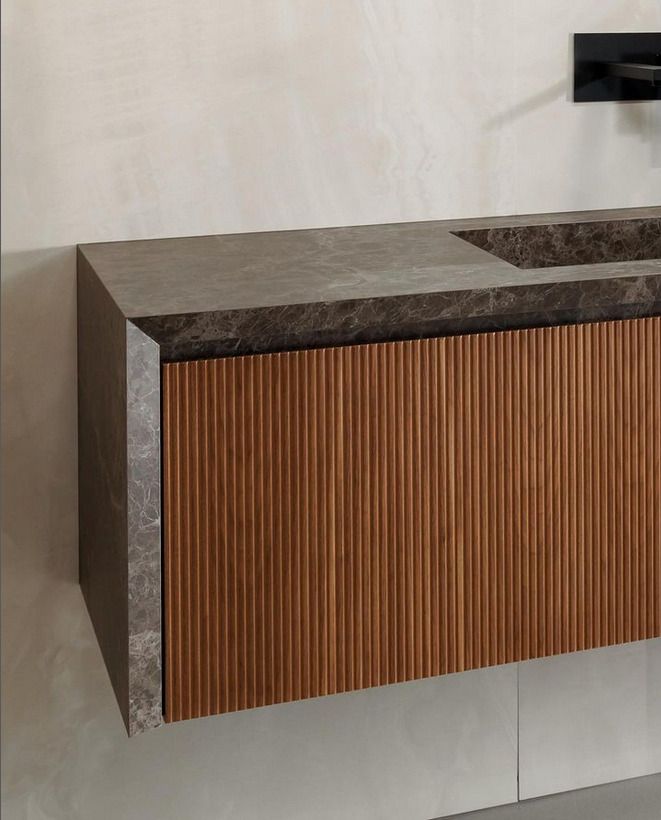A floating bathroom vanity with ribbed wood details and a contrasting stone countertop, showcasing a clean, modern look.