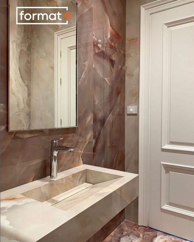 A luxurious bathroom design with a marble sink and walls, featuring a Format+ branded mirror, accentuating the earthy tones of the room.