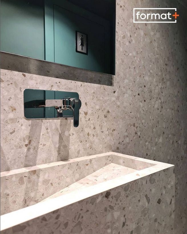 A terrazzo sink in a modern bathroom, highlighted by a polished chrome wall-mounted faucet.