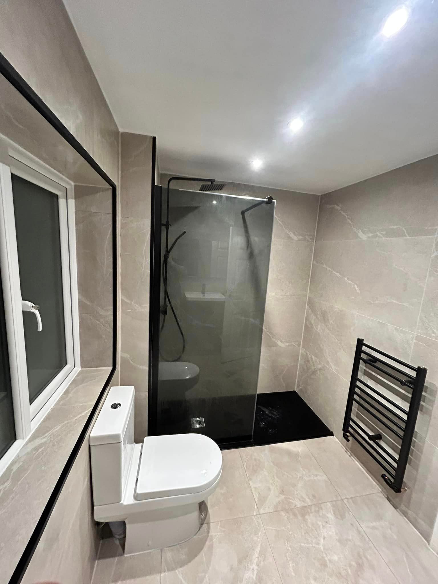 black Towel Ral with grey marble effect tiles used on the walls in this bathroom