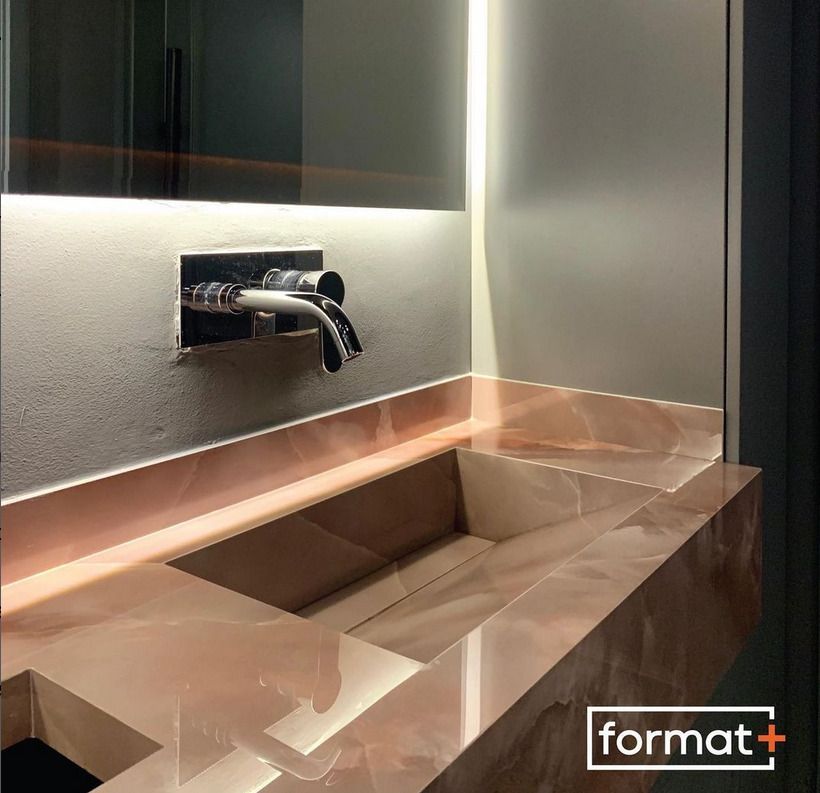 Modern bathroom sink featuring a polished stone finish, complemented by subtle ambient lighting and a sleek wall-mounted faucet.