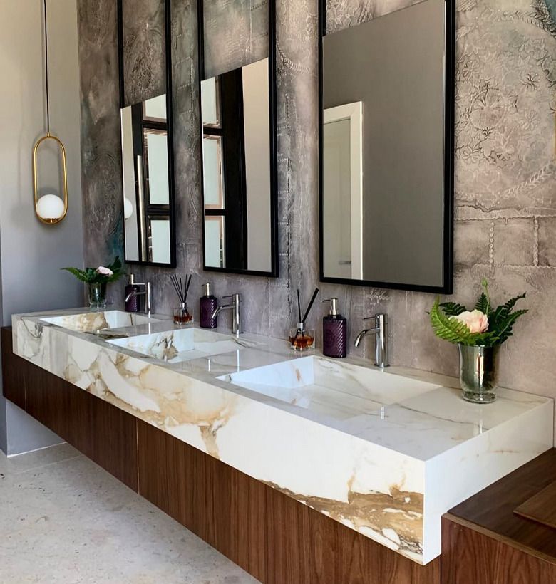 A contemporary bathroom with a marble countertop vanity, featuring warm wood tones and elegant wall mirrors.