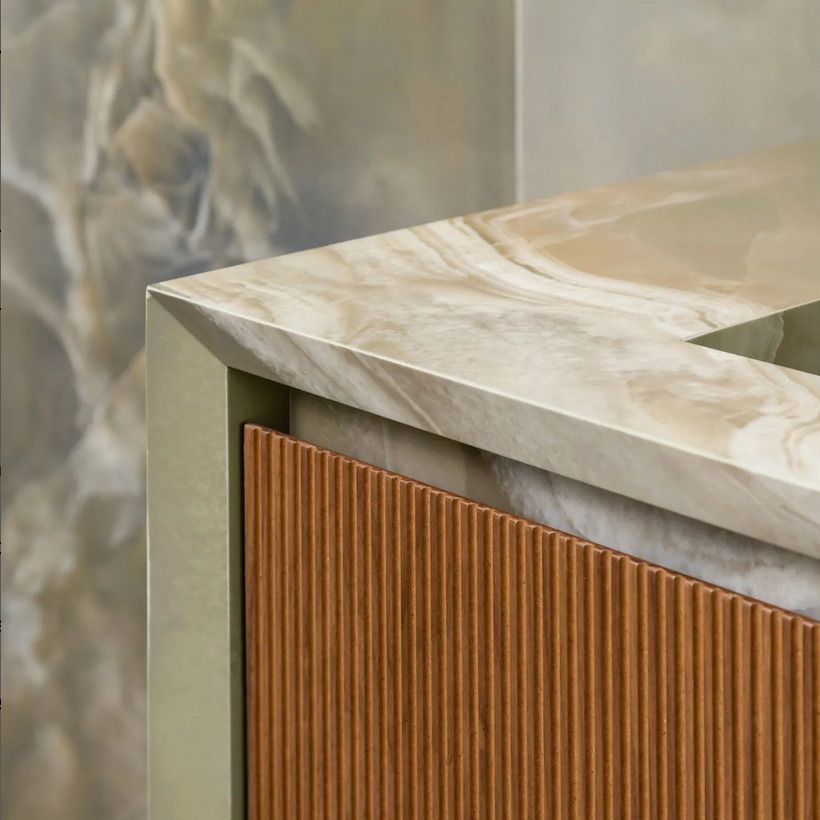 A detailed close-up of a beige marble vanity with a wood-panel cabinet, showcasing intricate tile design and luxurious materials.