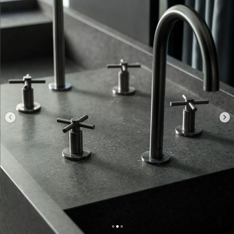 A dark grey stone sink with multiple cross-handle faucets, featuring sleek modern metal finishes.