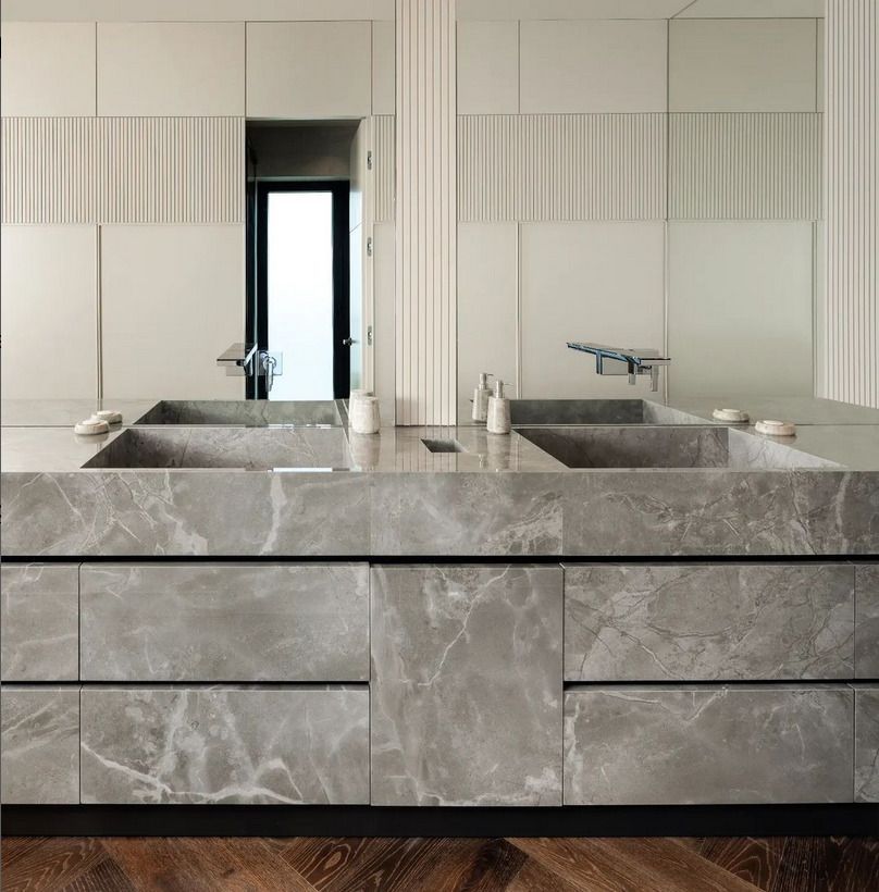 A modern bathroom with a sleek gray marble vanity, dual sinks, and a large wall mirror, highlighting minimalist design.