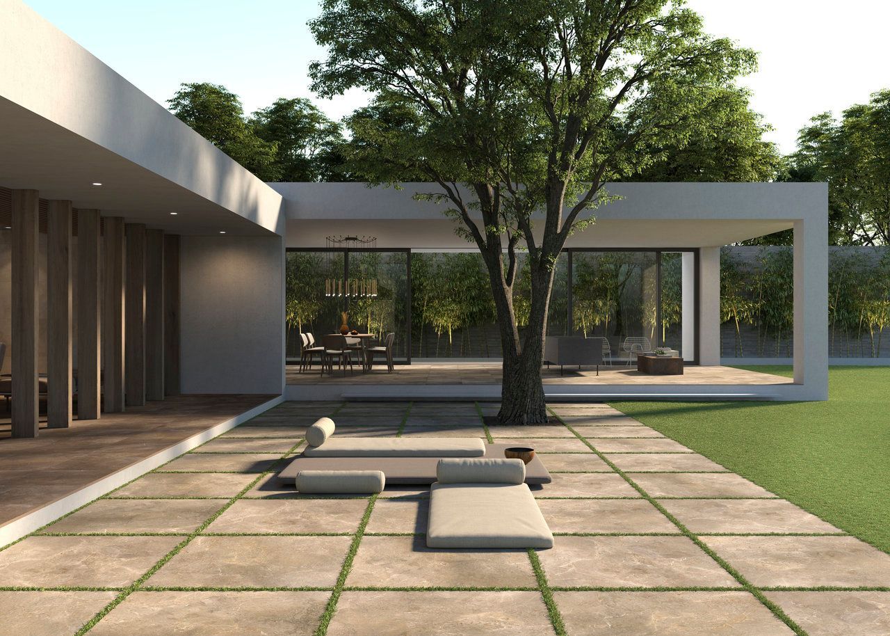 Minimalist patio with beige stone-look tiles featuring grass-filled joints. Modern lounger and wooden vertical elements add to the tranquil, architectural design.