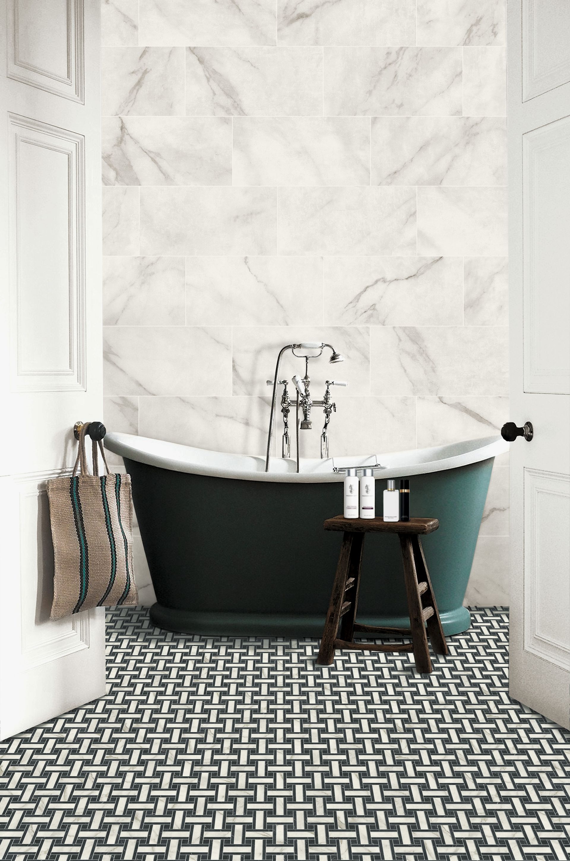 Charming bathroom with a vintage-inspired design featuring a freestanding clawfoot bathtub with a dark green exterior and white interior. The wall behind the tub is adorned with large, white marble tiles with subtle grey veining. The floor has a distinctive black and white woven pattern, adding a classic touch. A rustic wooden stool next to the bathtub holds various bath products. The bathroom is brightened by natural light coming through a nearby window, and a woven bag hangs on the door handle, contributing to the cozy and inviting atmosphere.