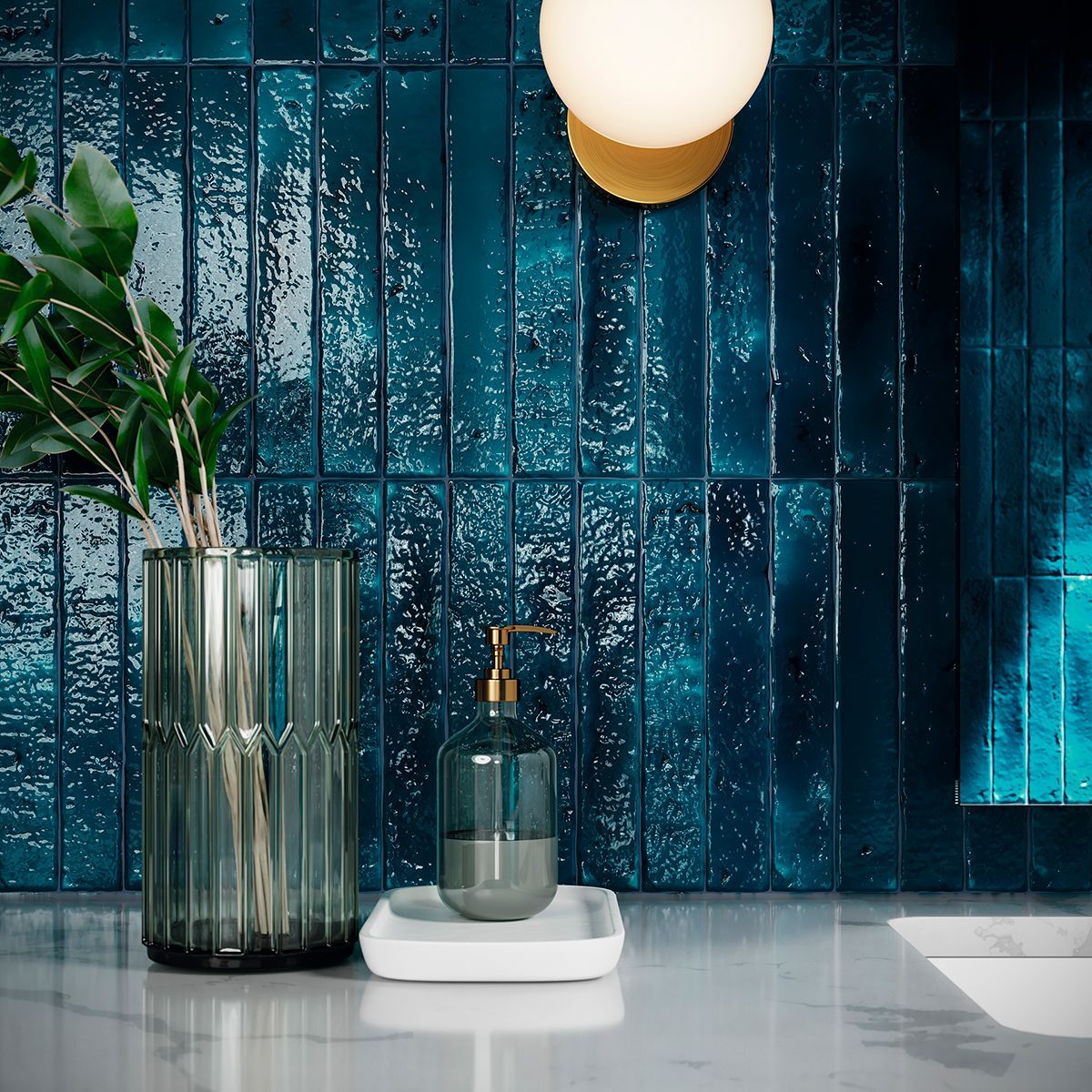 Close-up of a modern bathroom wall featuring glossy, distressed blue brick-effect tiles with a textured surface, complemented by a stylish green glass vase and a sleek soap dispenser, creating a sophisticated and contemporary look.