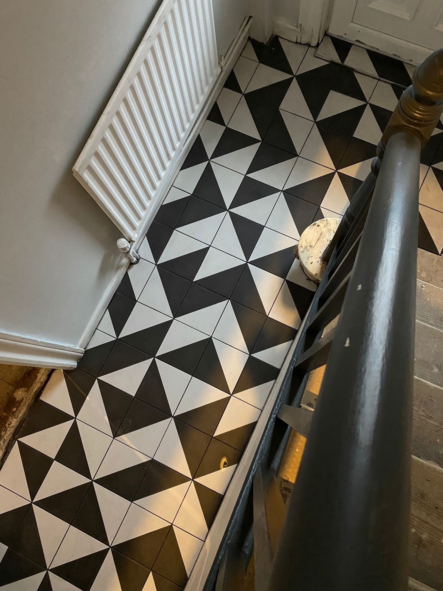 black and white floor with radiotor and stairs banister