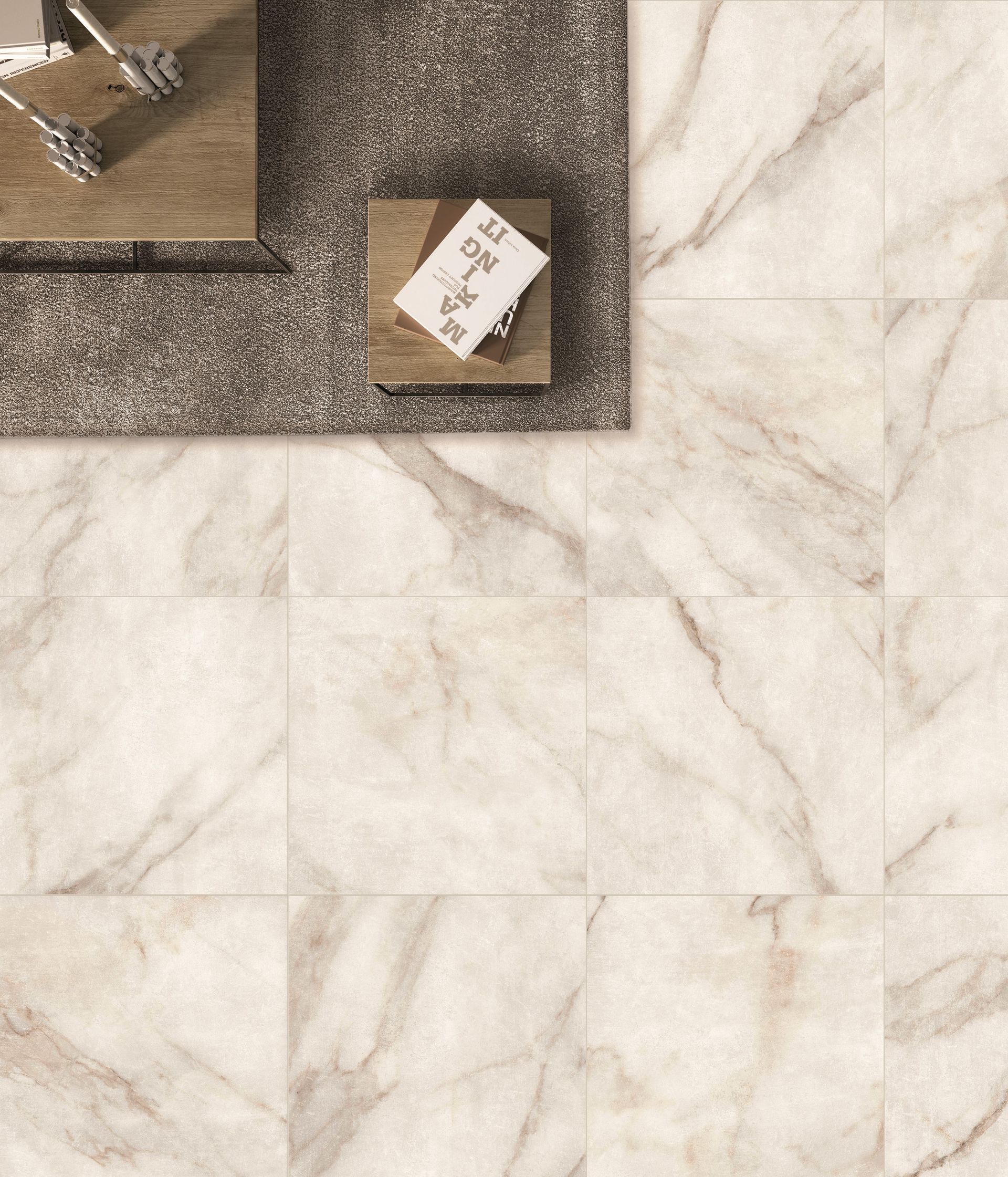 Overhead view of a modern interior space featuring elegant marble tiles with a light cream base and subtle gold veining. The flooring creates a luxurious and warm atmosphere. A small wooden table with a book and decorative items sits on a grey textured rug, contrasting with the smooth and polished surface of the tiles. The arrangement and materials enhance the sophisticated and cozy ambiance of the room