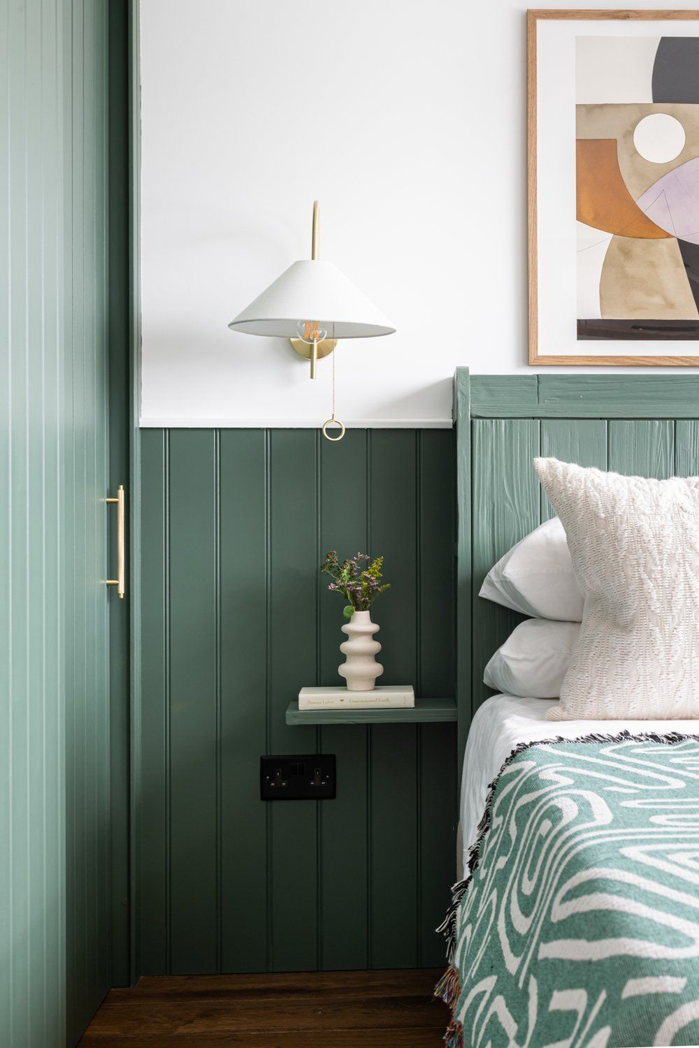 Green bedframe with plants and pillows and wall tiles