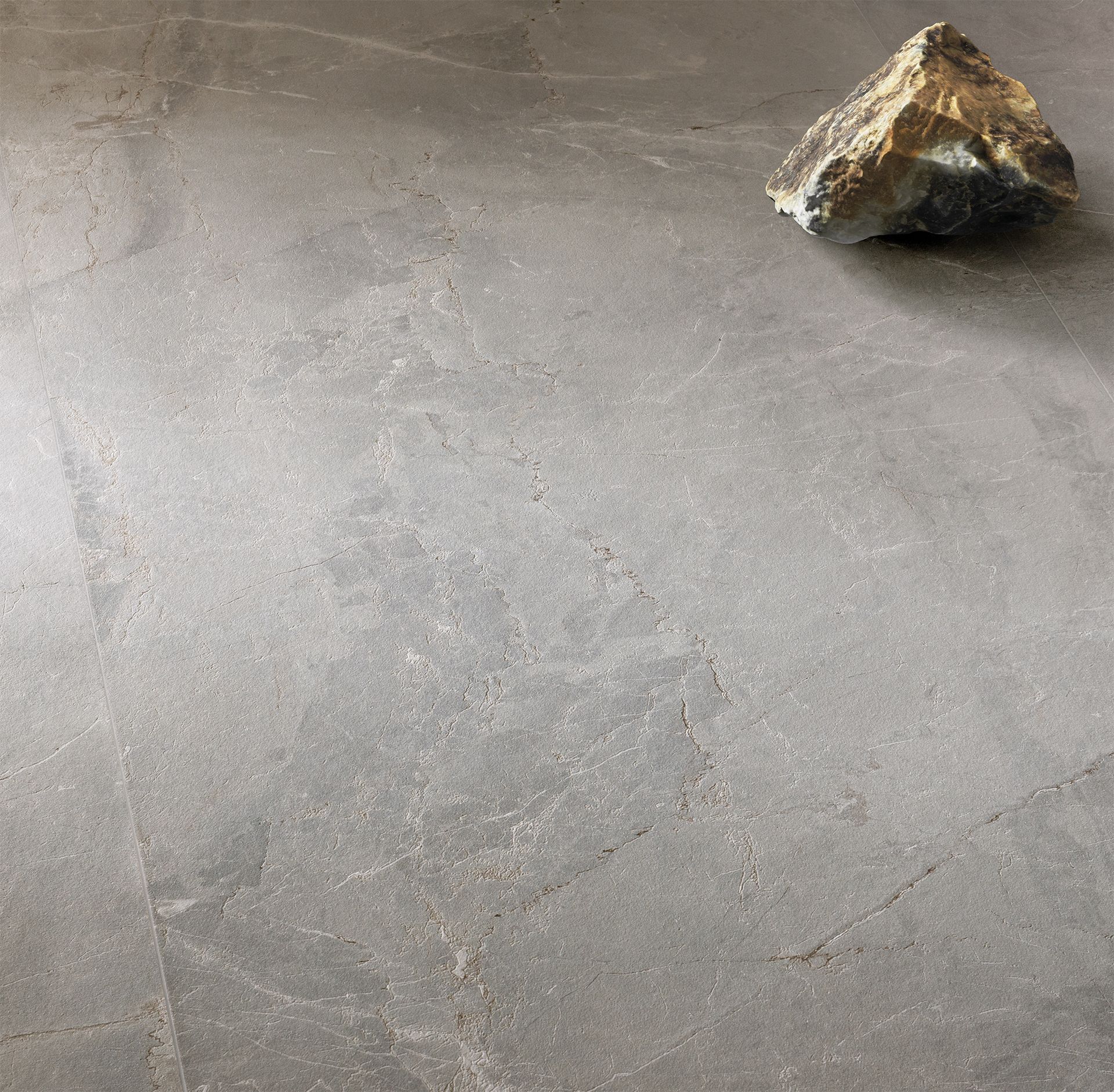 A close-up shot of dark gray stone tiles showcasing their natural texture, with a single decorative stone placed on the surface for contrast.