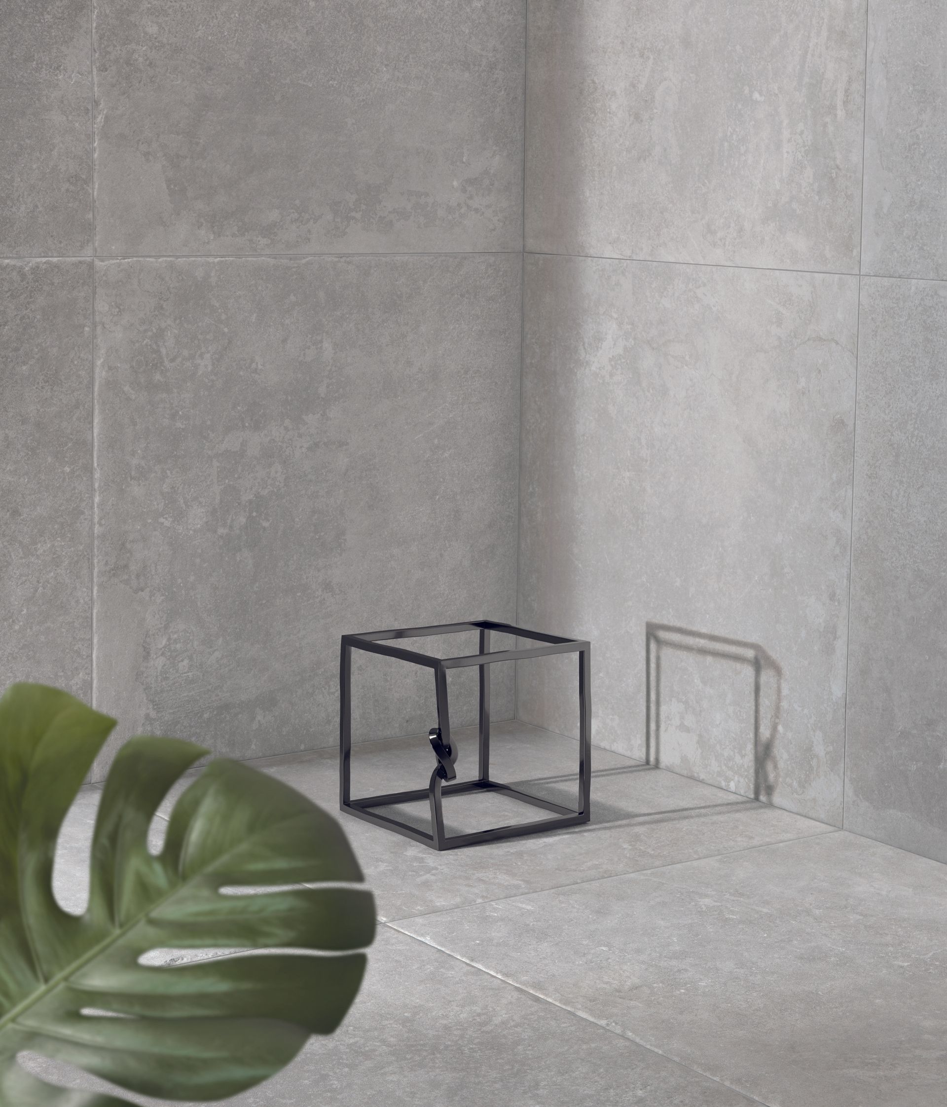 limestone effect tiles with a metal frame cube with a plant leaf