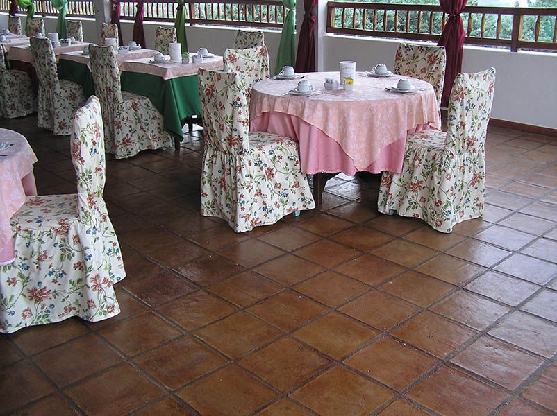 café with natural terracotta square floor tiles under the pink cloth tables