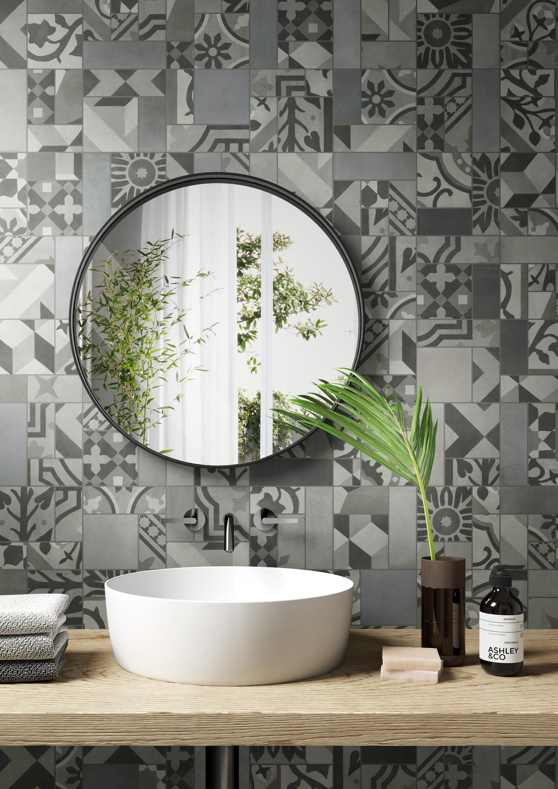 Pattern wall tiles behind a mirror reflecting leaves