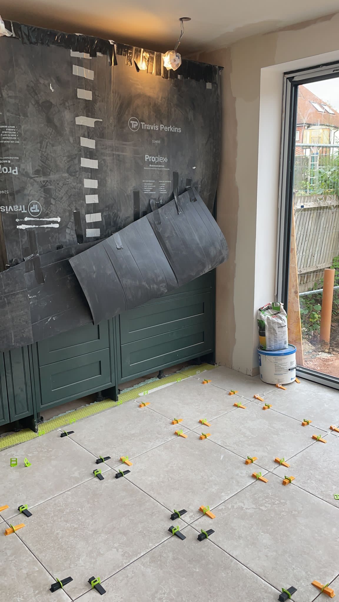 Kicthen Floor tiles, Pierre tumbled blanco 600x600, Levelling clips, Dural matting, Dark Green kitchen cupboards.
