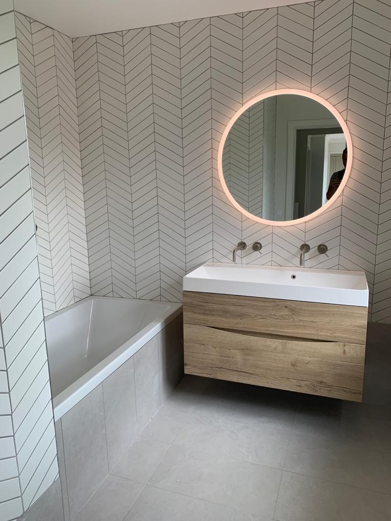 Chevron wall tile in bathroom with light up mirror on the wall