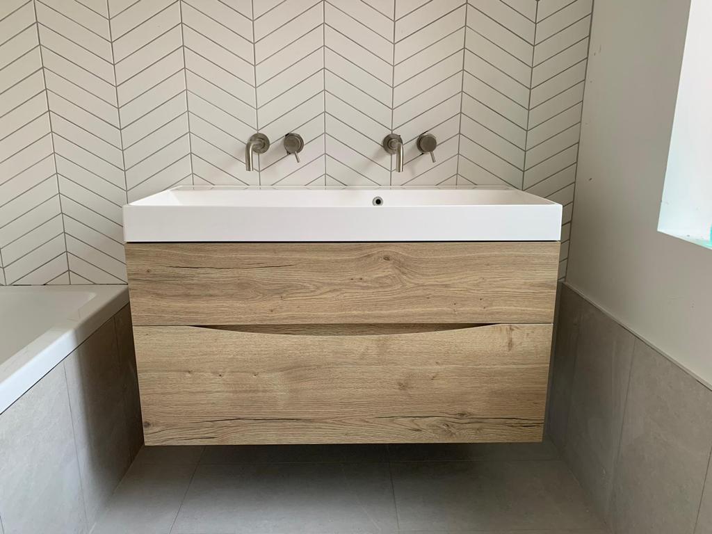 close up of wooden cupboard in front of white chevron matt tiles
